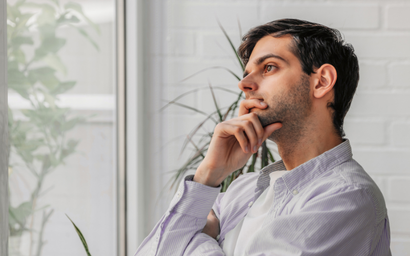 Mann sieht verträumt aus dem Fenster und hat die rechte Hand am Mund gestützt, Reiki, Elke Maria Becker, Niedernberg bei Aschaffenburg